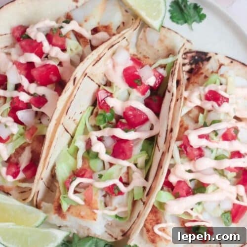 Three soft tacos with slaw and white fish filling.