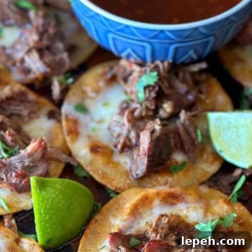 A spread of birria tacos with lime wedges.