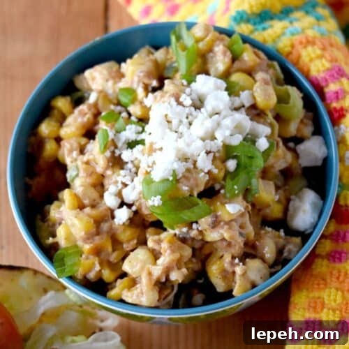 a bowl of corn salad with cojito cheese and a creamy dressing.