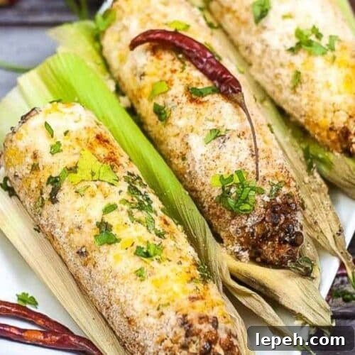 ears of Mexican street corn on a plate, coated with cheese.
