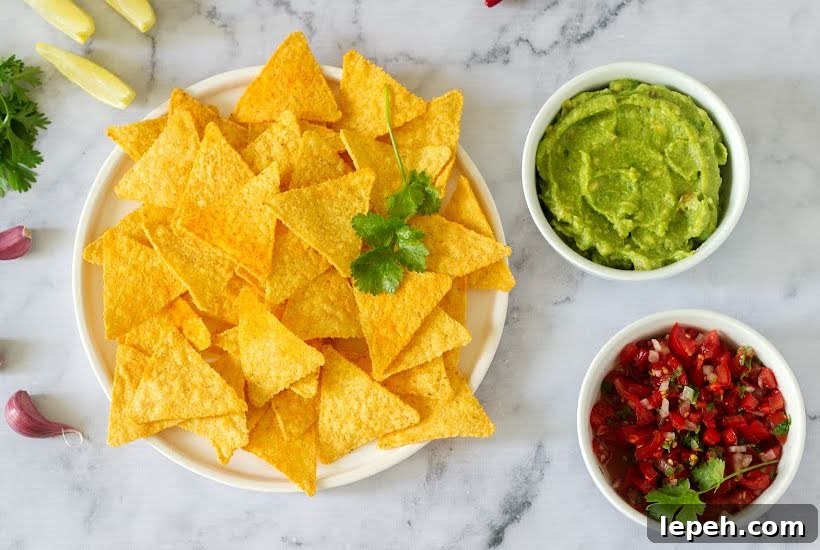 Plate of tortilla chips with bowls of salsa and guacamole.