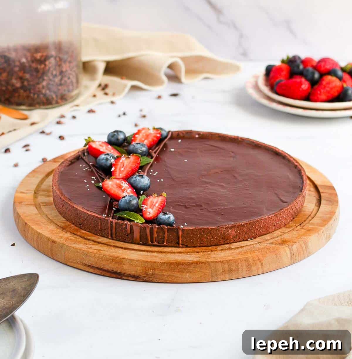 Chocolate Tart on a round wooden board over a white surface.