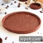 Baked chocolate crust on a white surface surrounded by chocolate chunks.