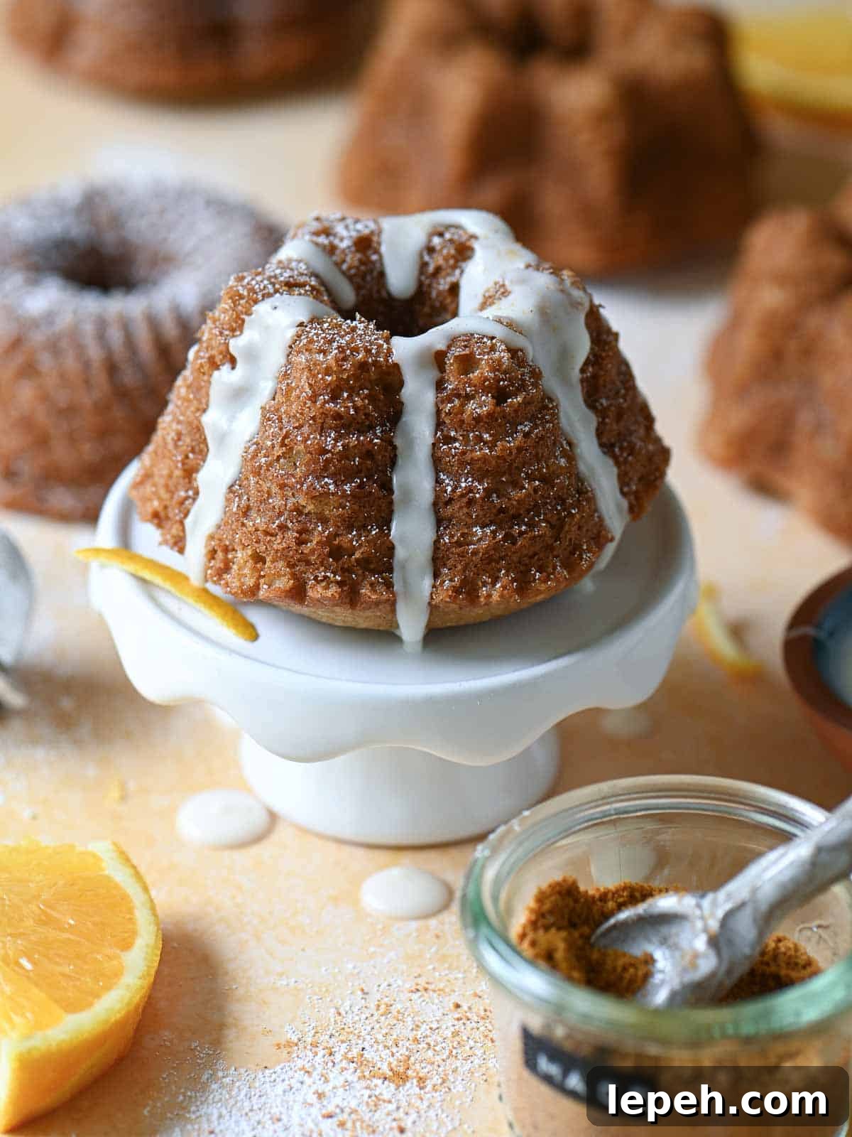 A mini glazed bundt cake on a small white cake pedestal.