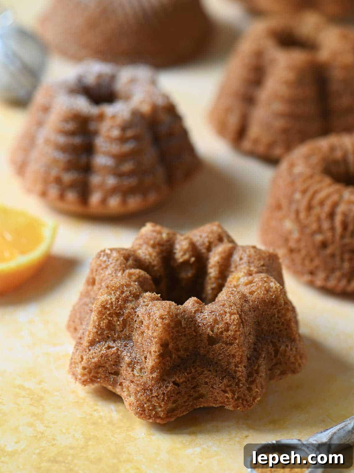 Close-up of mini bundt cakes on an orange surface.