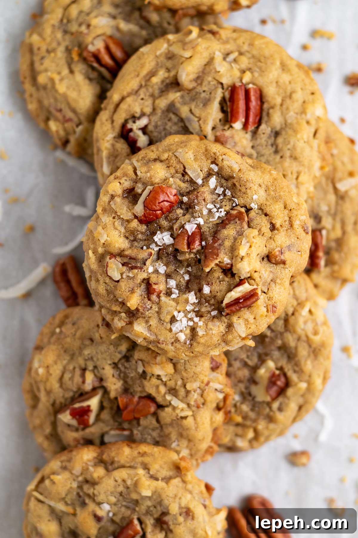 coconut pecan cookies on parchment paper with extra pecans