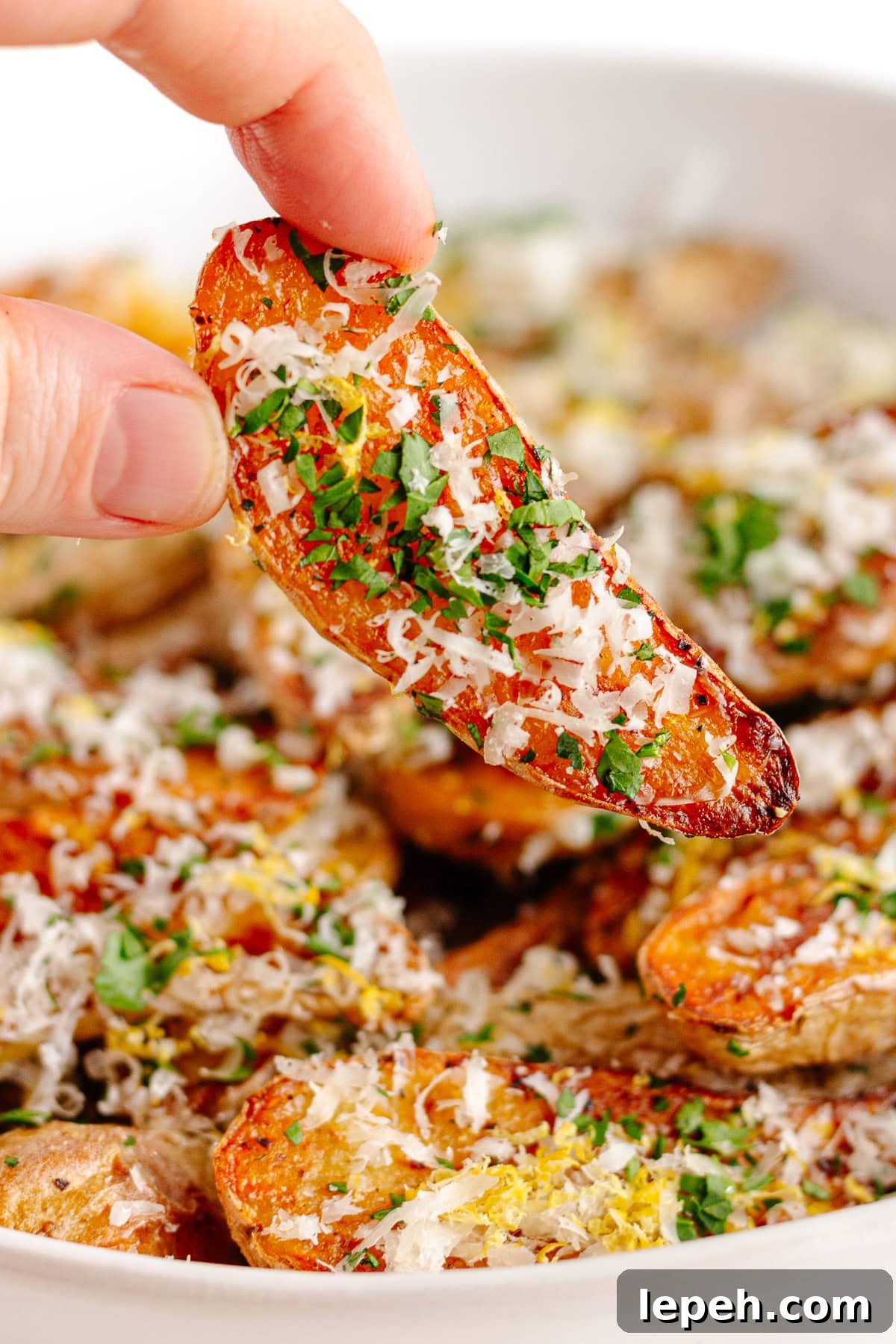Hand picking up a truffle parmesan fingerling potato from bowl.