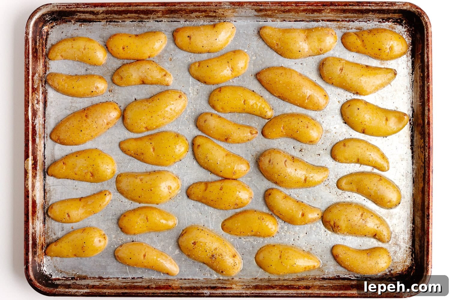 Halved fingerling potatoes arranged cut side down on a baking sheet for roasting.
