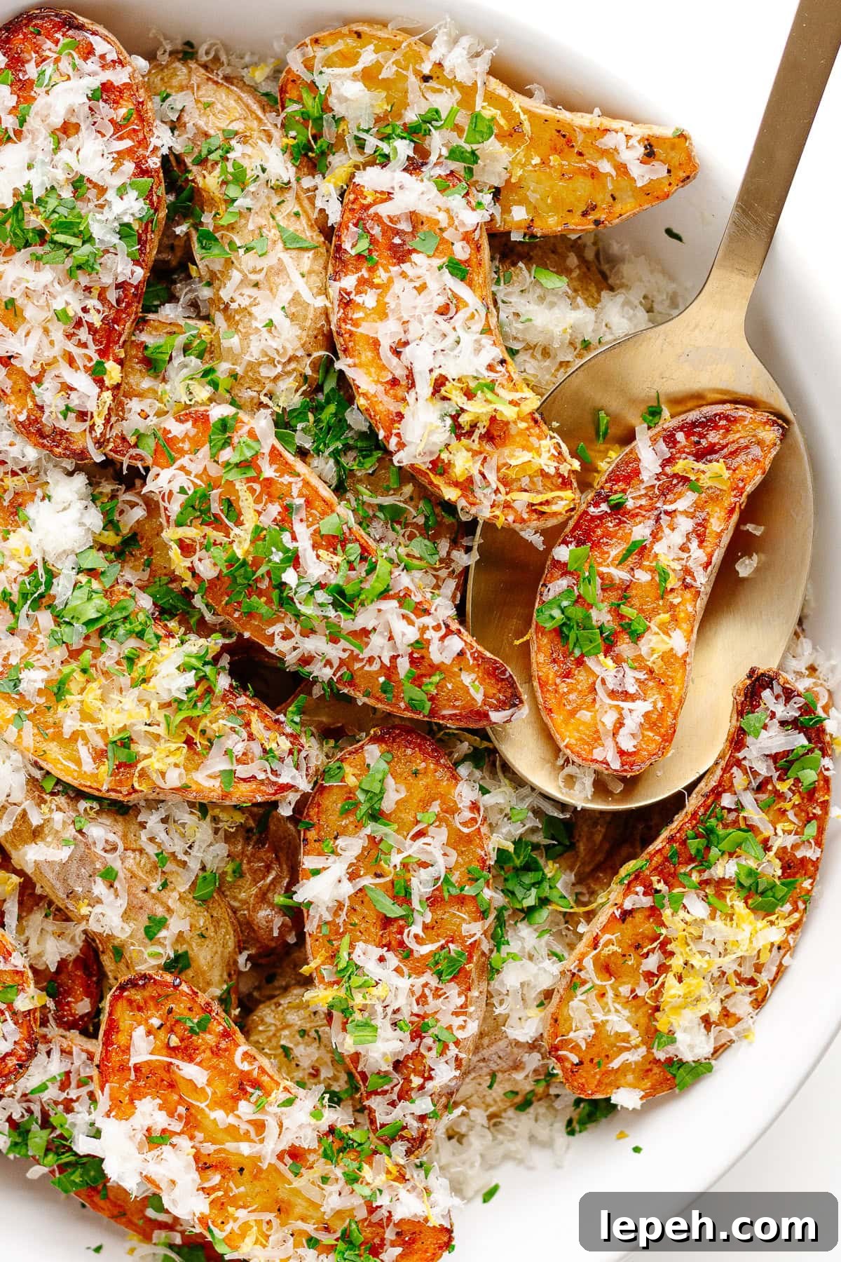 Roasted fingerling potatoes with truffle and parmesan in a serving bowl with serving spoon.