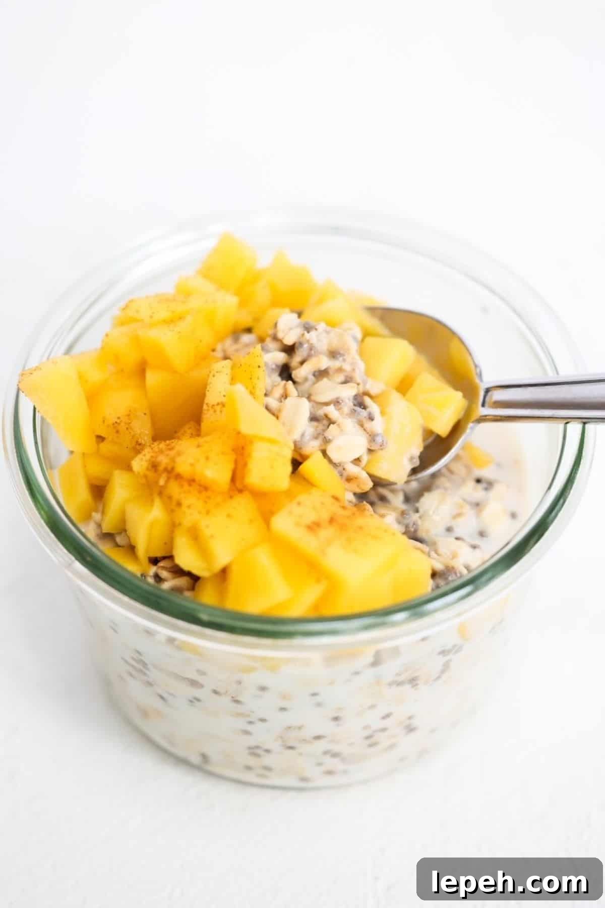 Mango overnight oats in a glass jar with a spoon.