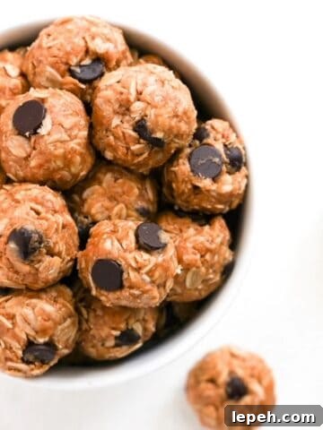 Top view of one white bowl filled with bliss balls. A few bliss balls are to the right of the bowl.