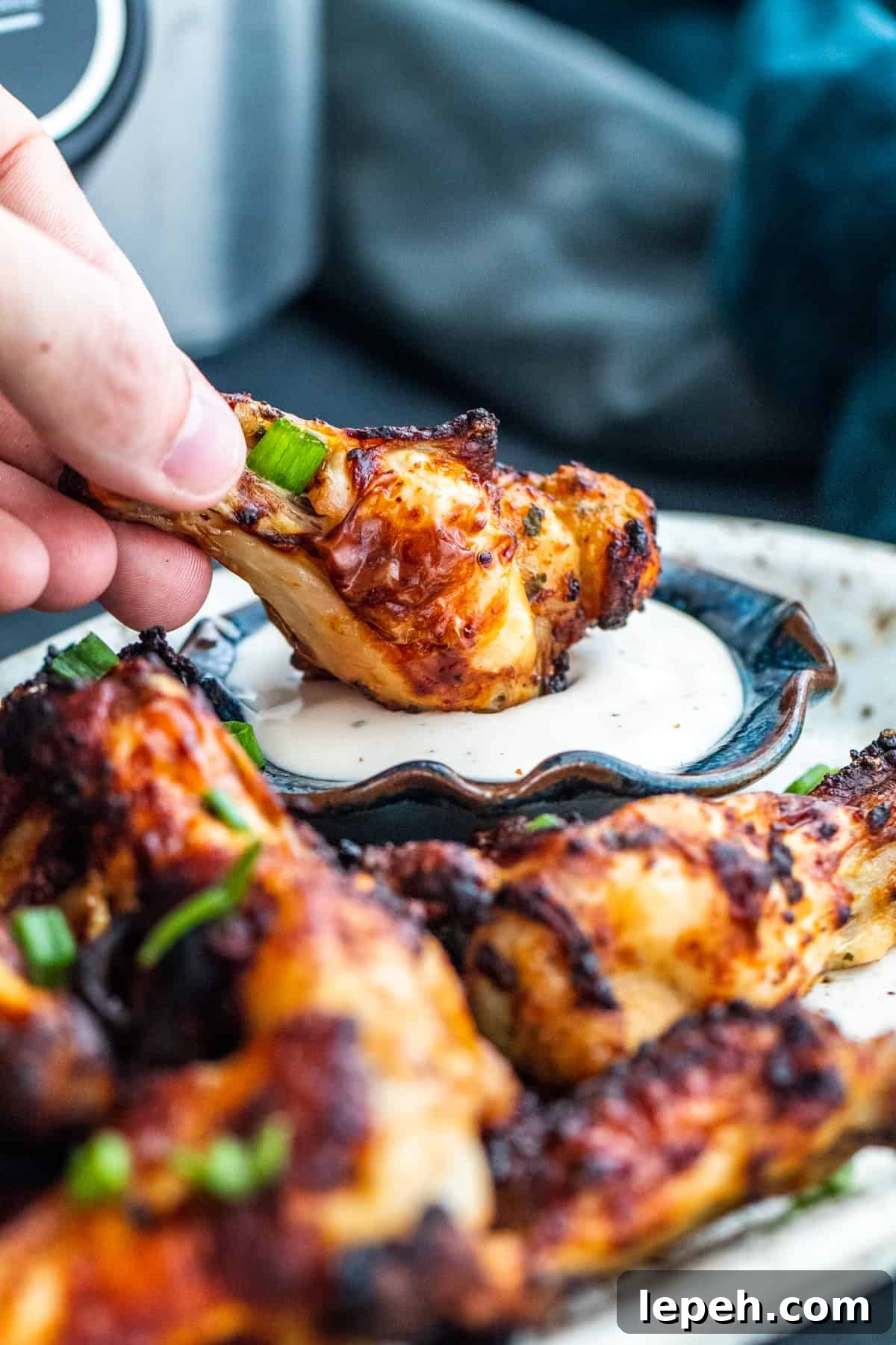 Hand dipping wing into small bowl of ranch.