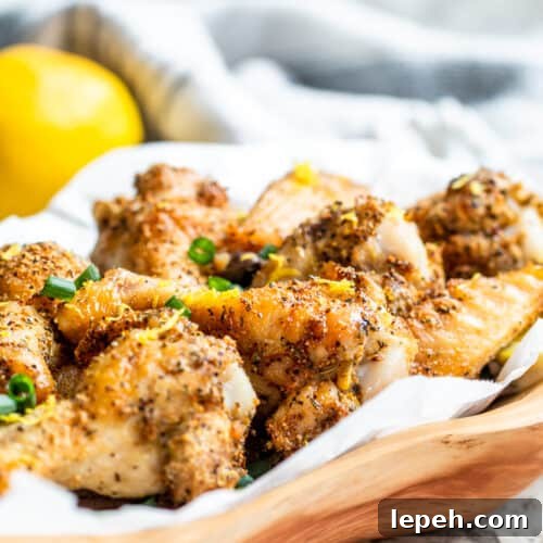 Wooden bowl filled with lemon pepper wings on white counter.