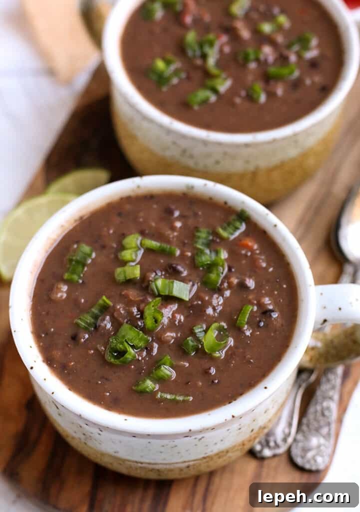 two bowls of vegan black bean soup on a wooden cutting board 