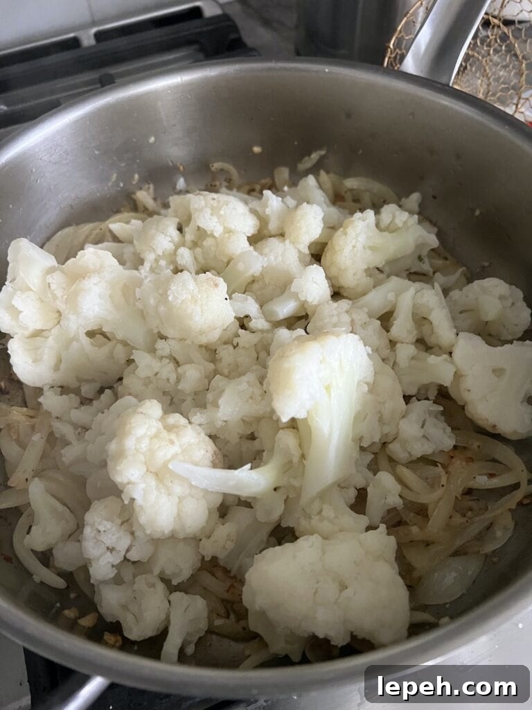 Sautéing cauliflower in skillet with onions and garlic in olive oil.