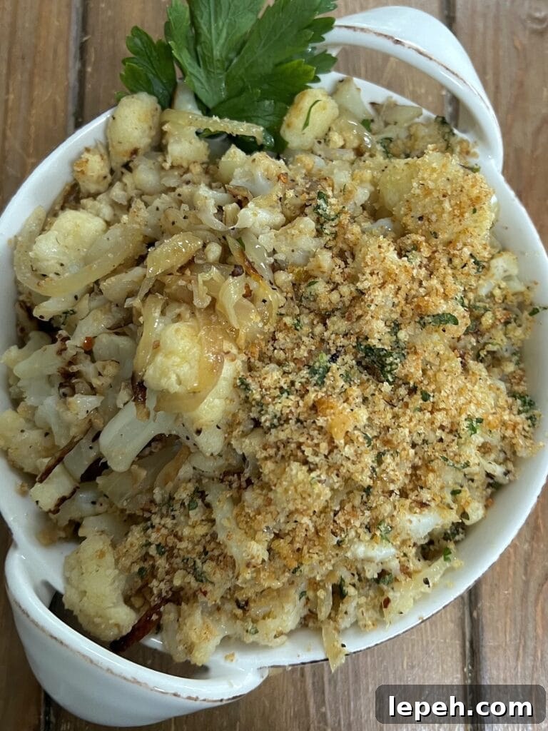 Smashed italian sauteed cauliflower in white serving dish with parsley garnish.