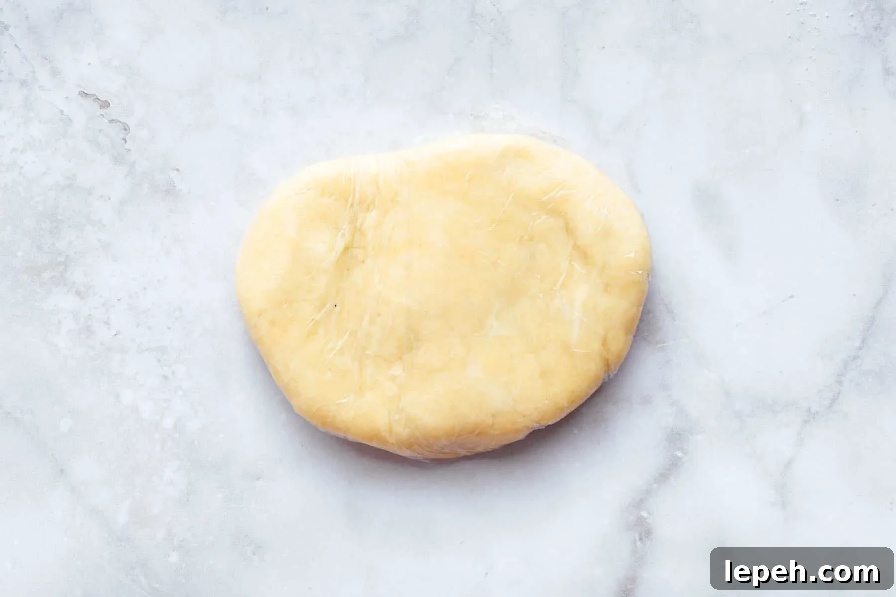 Pale yellow pastry dough oval on marble surface.