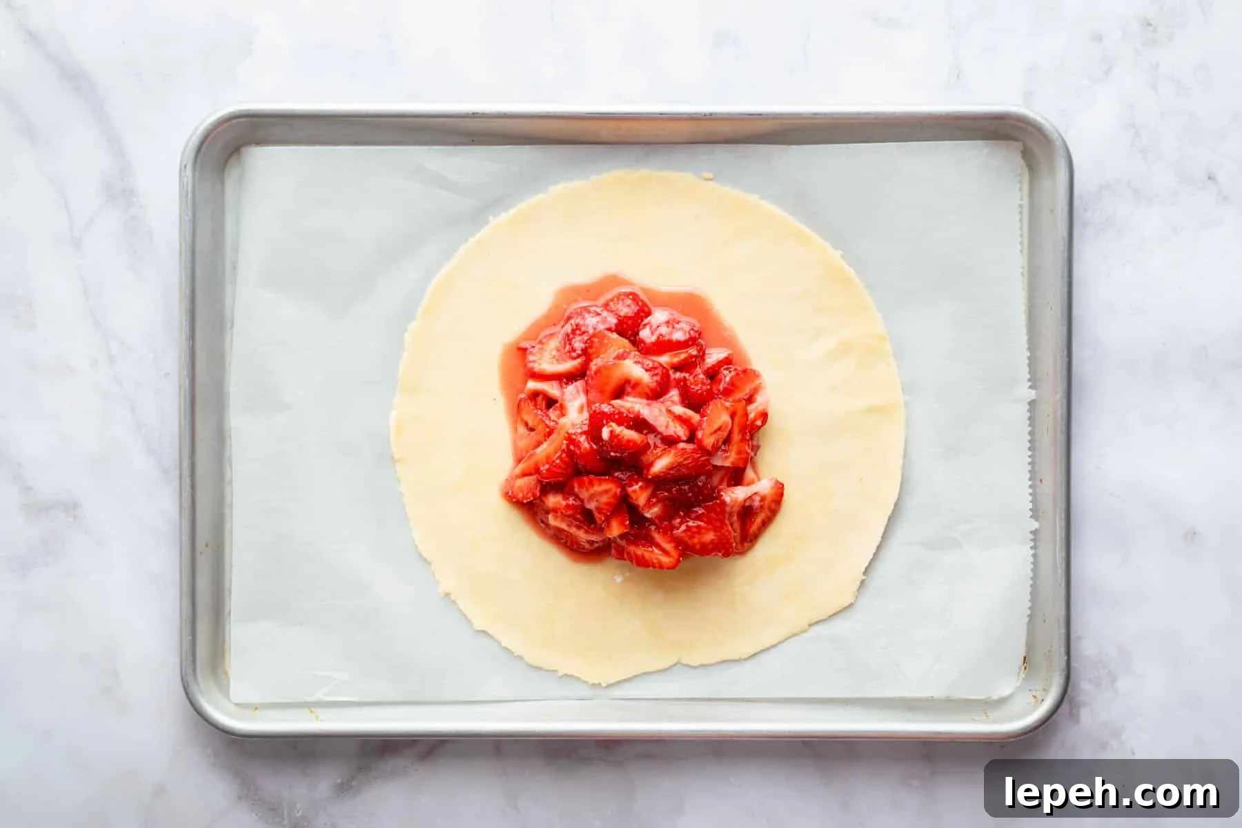Dough circle with sliced wet strawberries piled in center.