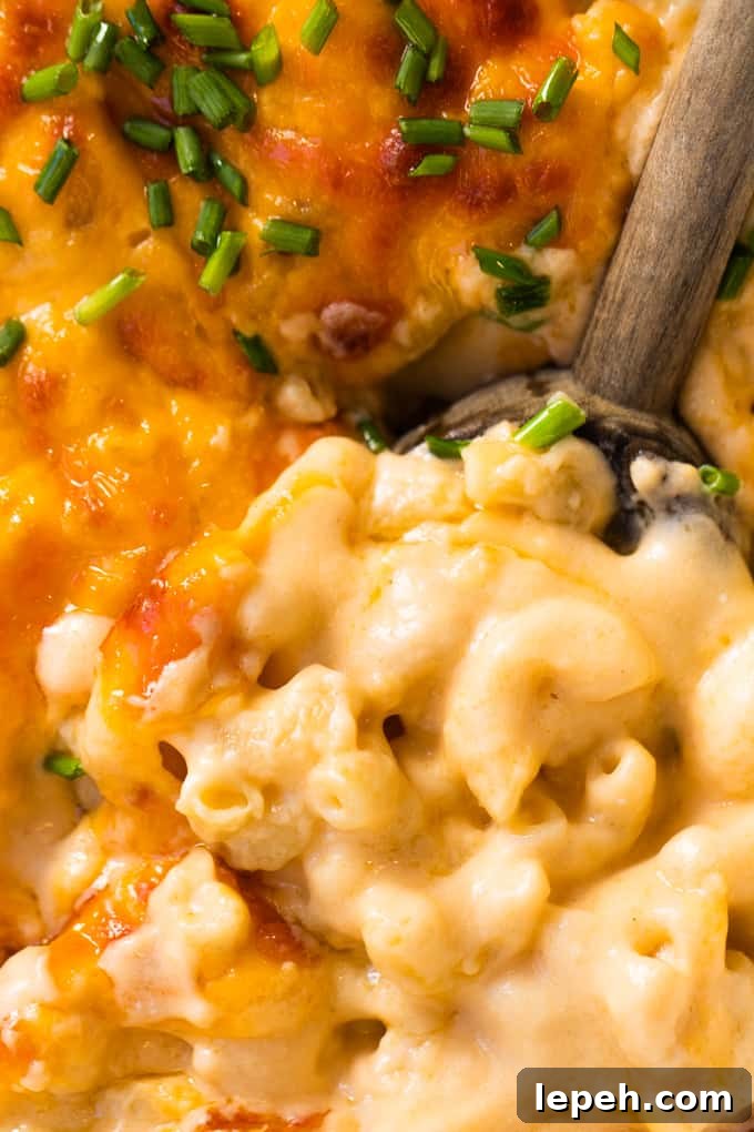 Wooden spoon in homemade baked macaroni and cheese showing still creamy consistency after baking.