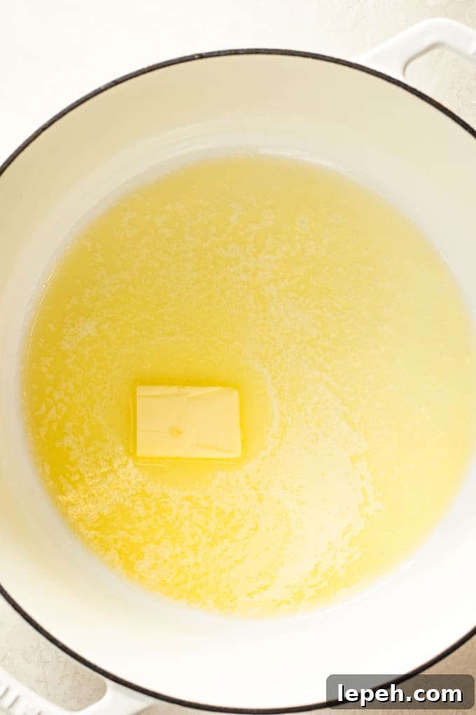 Butter melting in a large dutch oven pot for making homemade cheese sauce for macaroni and cheese.