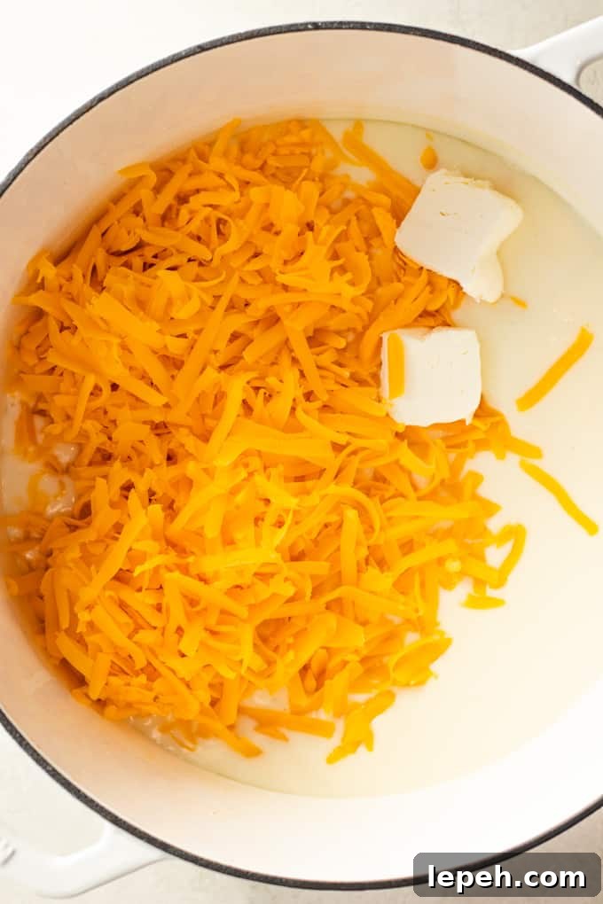 Butter and shredded cheese added to a roux for making homemade cheese sauce for macaroni and cheese.