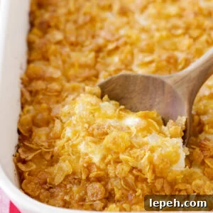 Funeral potatoes being scooped out of casserole dish.