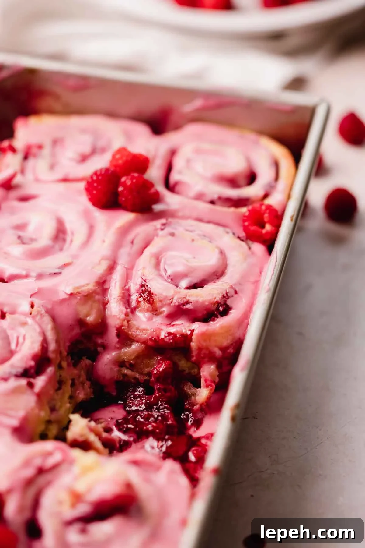 raspberry rolls in pan with gooey filling at the bottom of the pan