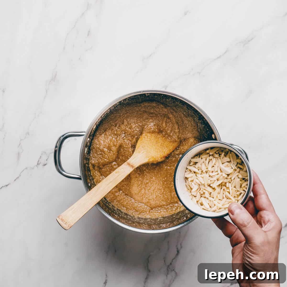 adding slivered almonds to a pot filled with Greek halva.