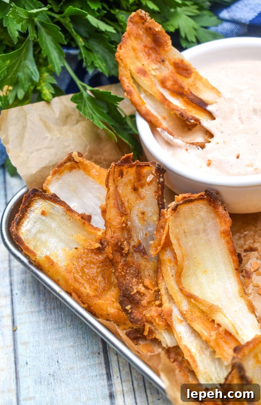 a close up of fried onion petals resting on a brown parchment paper lined food tray