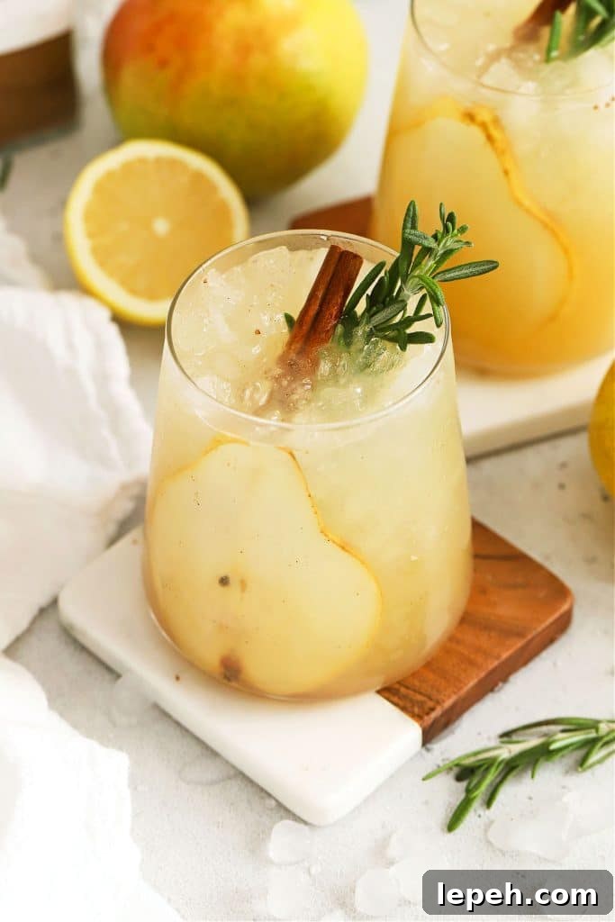 fresh pear punch with slices of pear, cinnamon sticks, and fresh rosemary