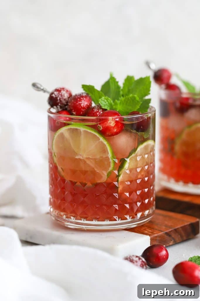 Cranberry lime mocktails topped with sugared cranberries, lime slices, and fresh mint