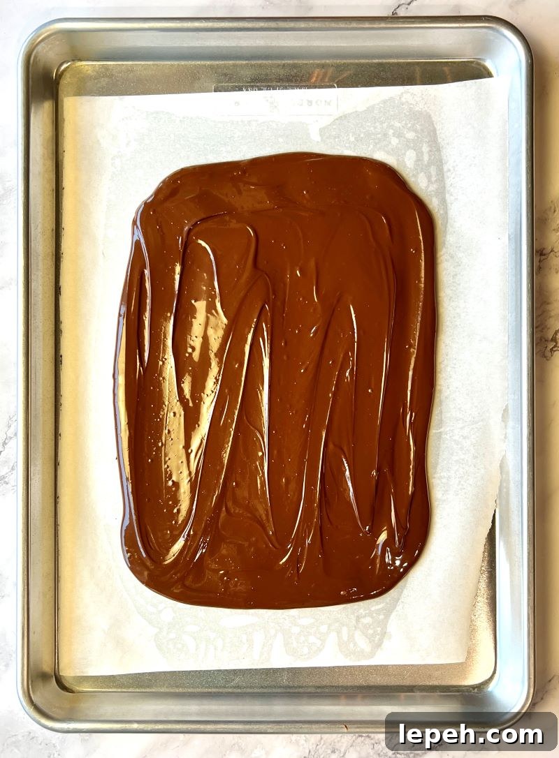 Melted chocolate spread out on sheet pan into a rectangle.