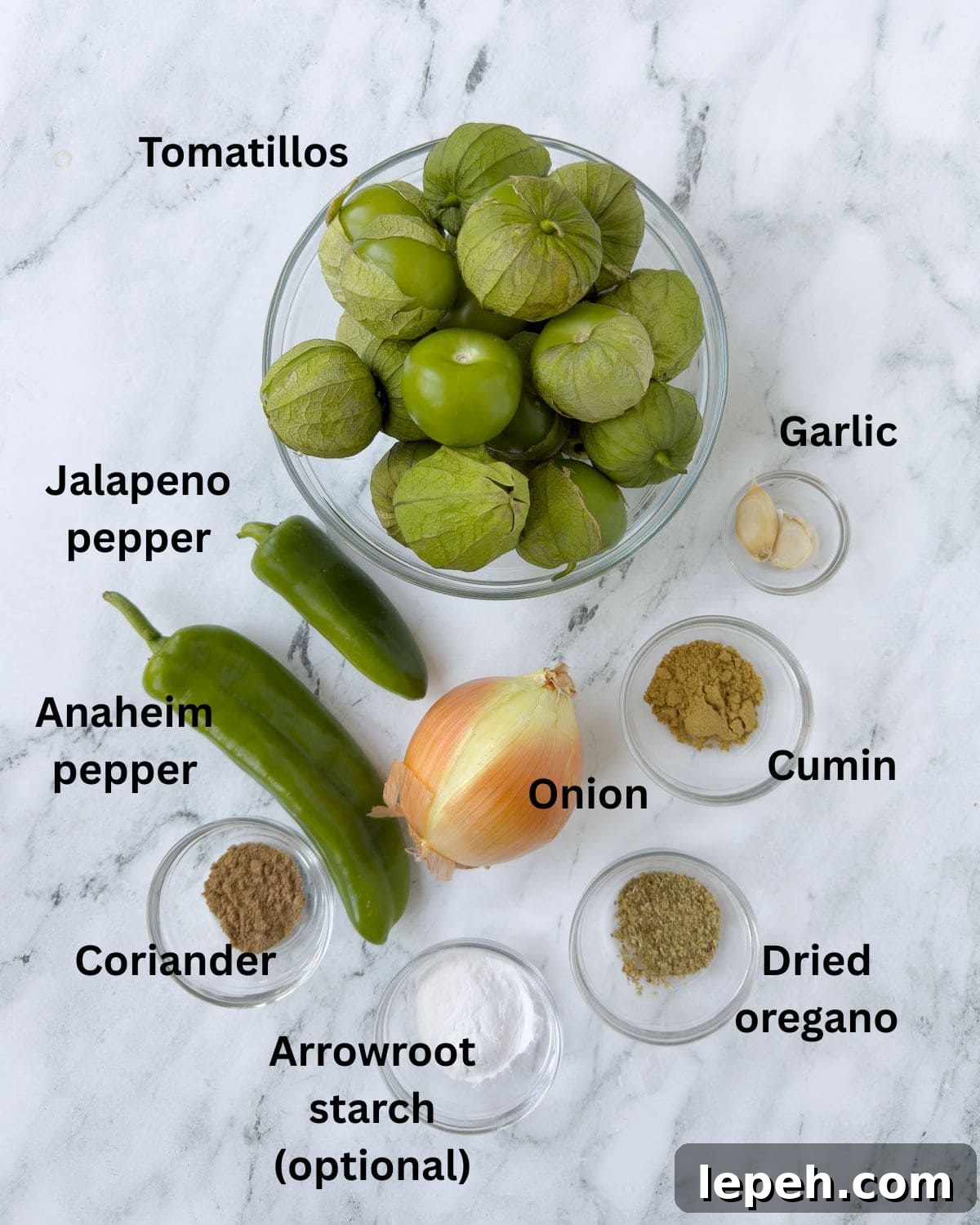 Tomatillos, onion, chili peppers, garlic and spices for making green enchilada sauce in prep bowls.