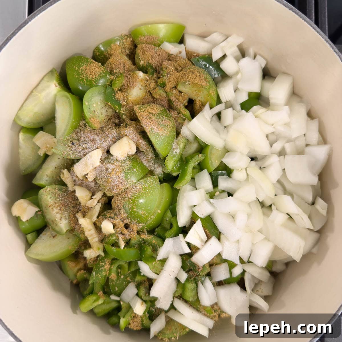 Ingredients for green enchilada sauce in a dutch oven ready for simmering, with spices, onions. 