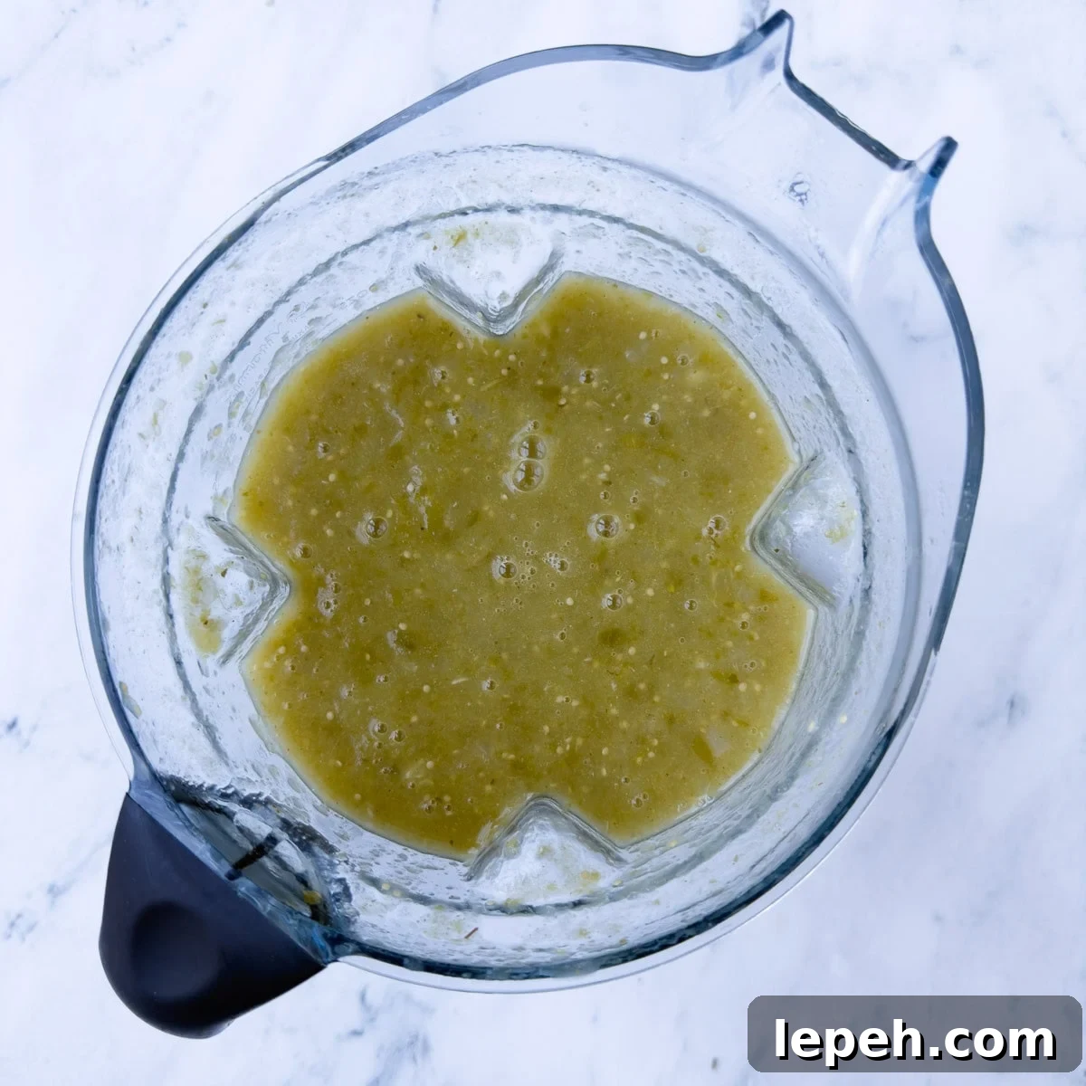 Pureed green tomatillo sauce in a blender container. 