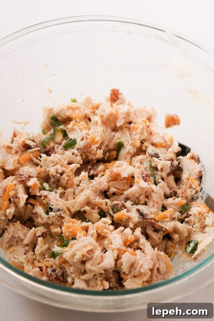 mixed chicken salad in a large bowl with bacon and cheddar cheese