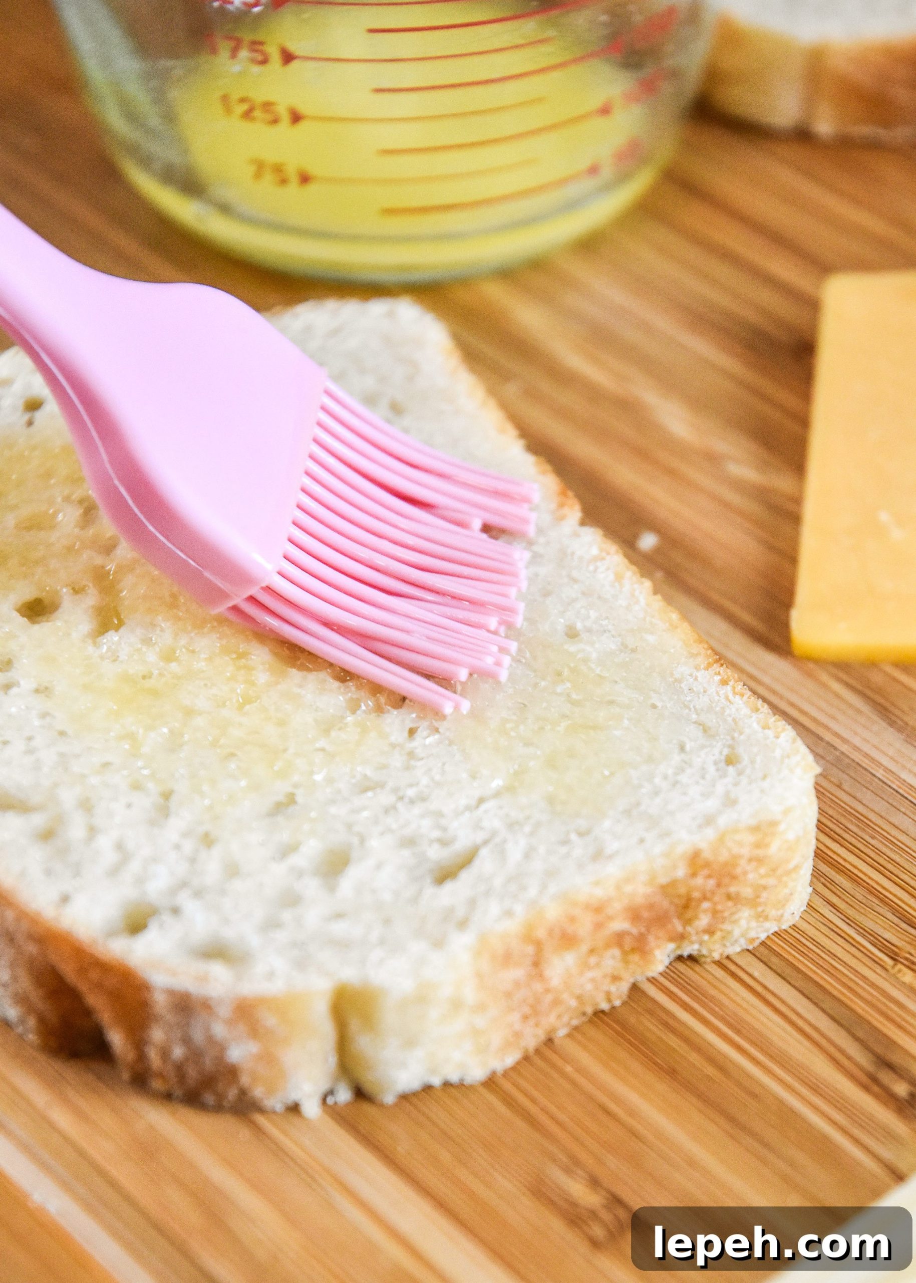 brushing butter on bread to make a grilled cheese sandwich