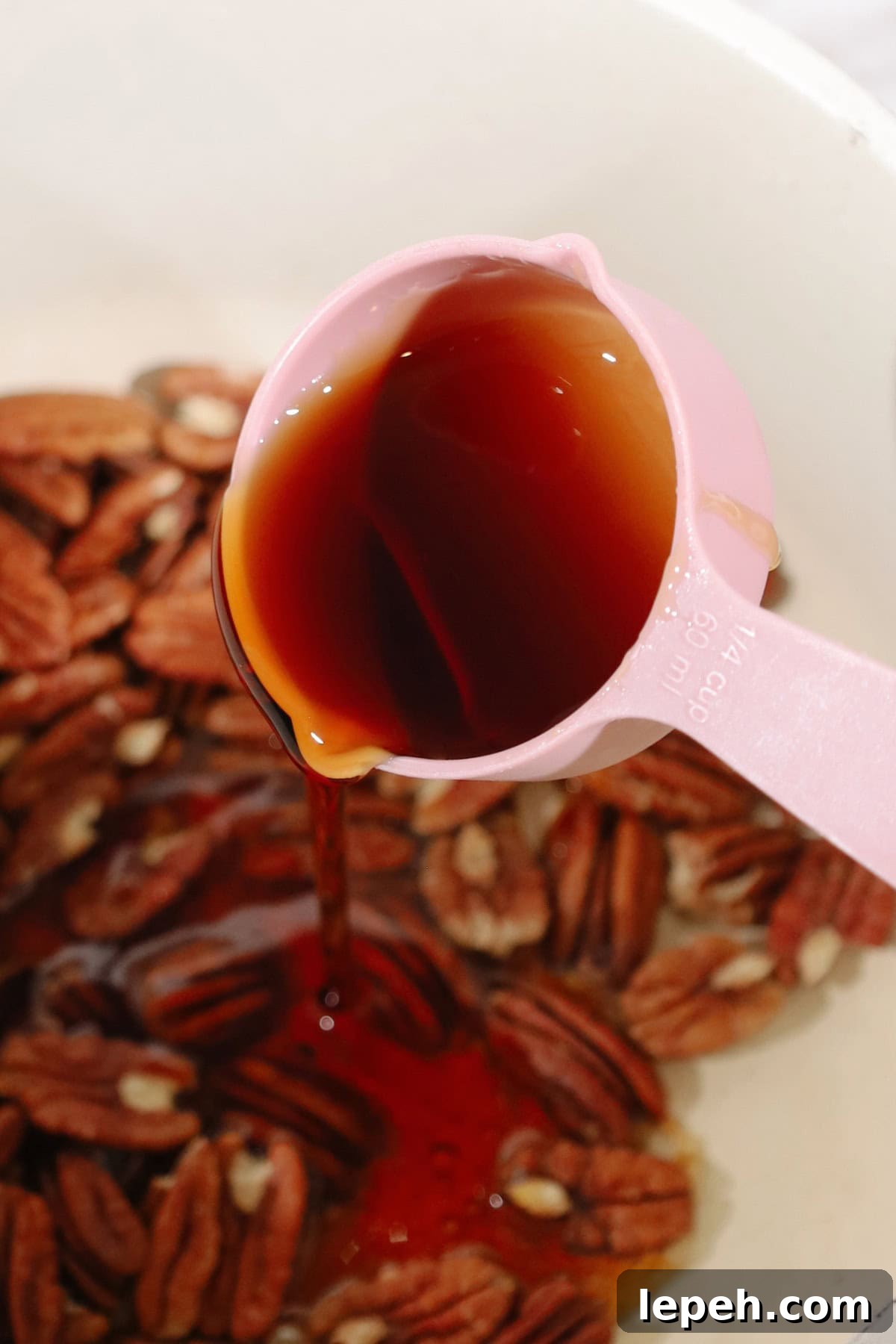 Maple syrup being poured on top of pecans.