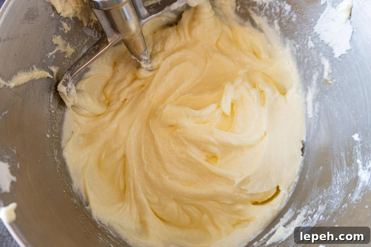 oil and eggs mixed into butter and sugar to create a batter, in a metal bowl.