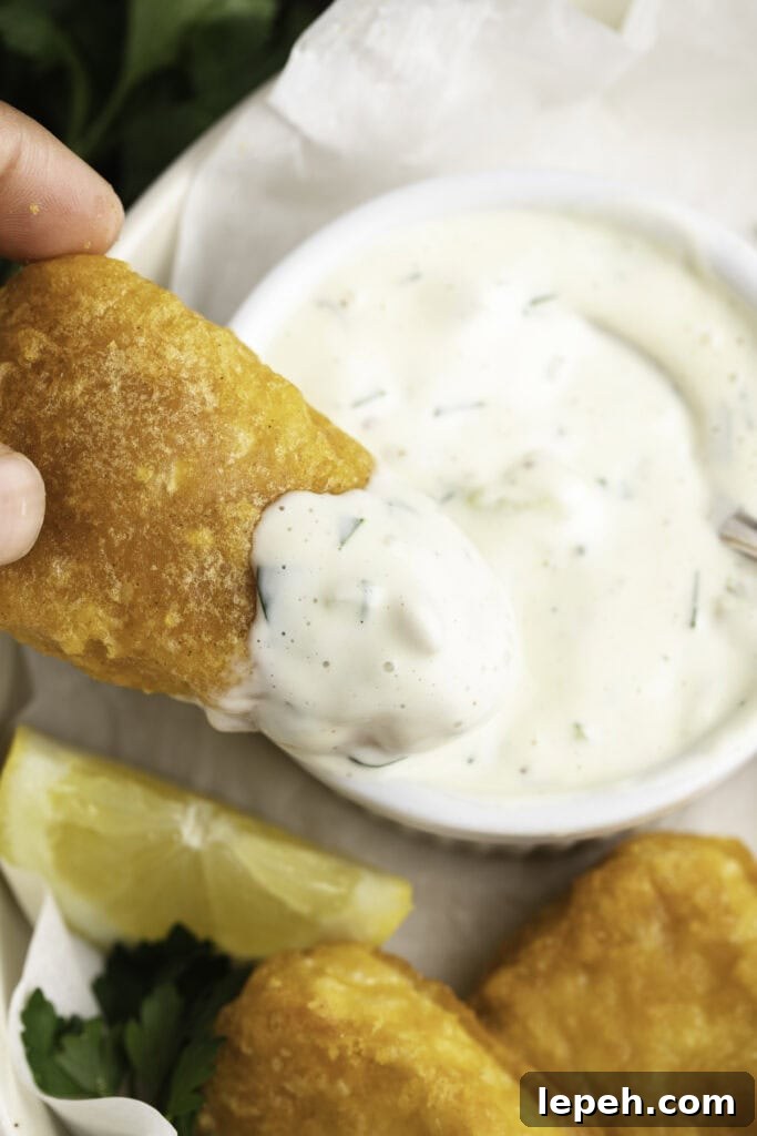 Vegan tartar sauce on a piece of vegan breaded and fried fish.
