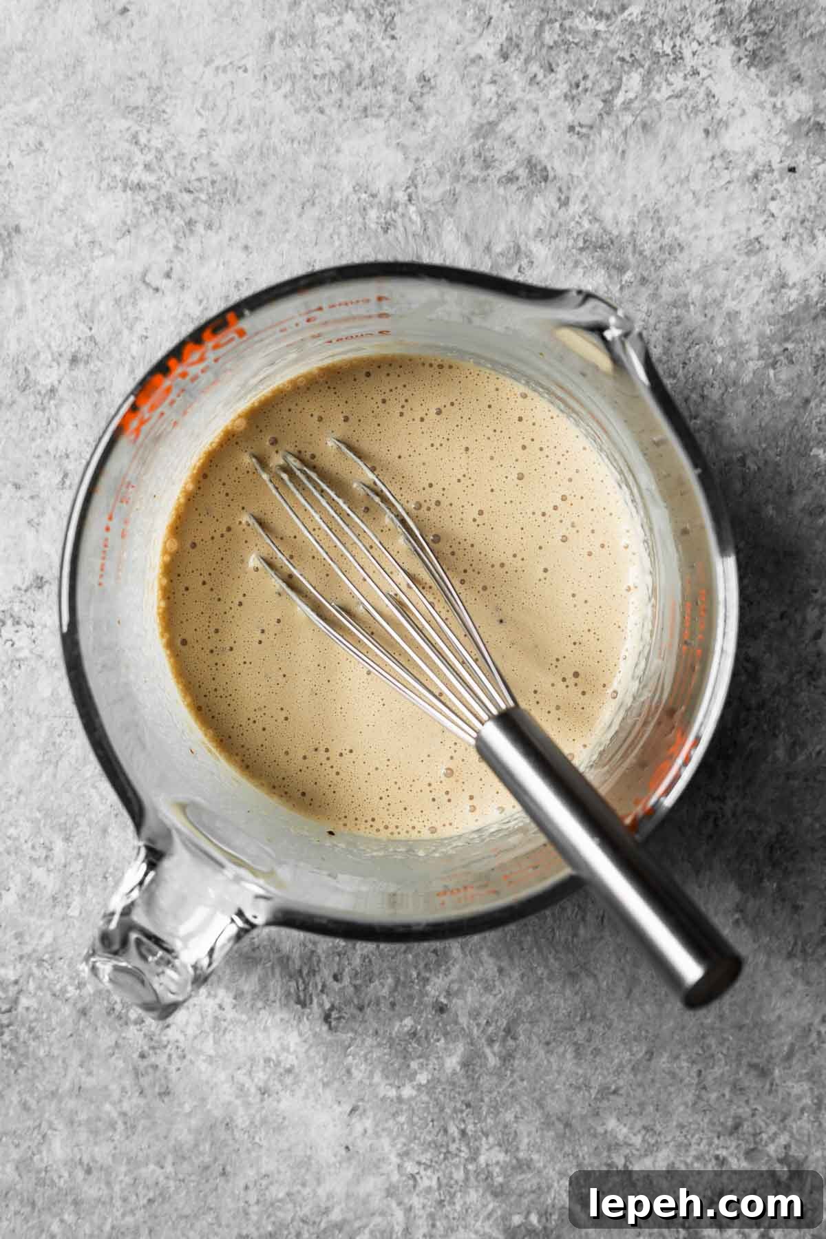 Cream, sugar and instant espresso powder whisked together in a glass measuring container.