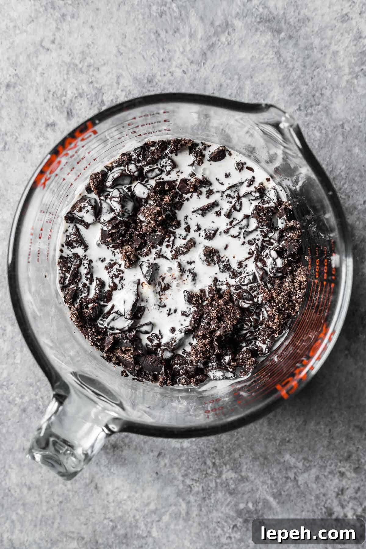 Hot cream poured onto chopped chocolate in a glass measuring container.