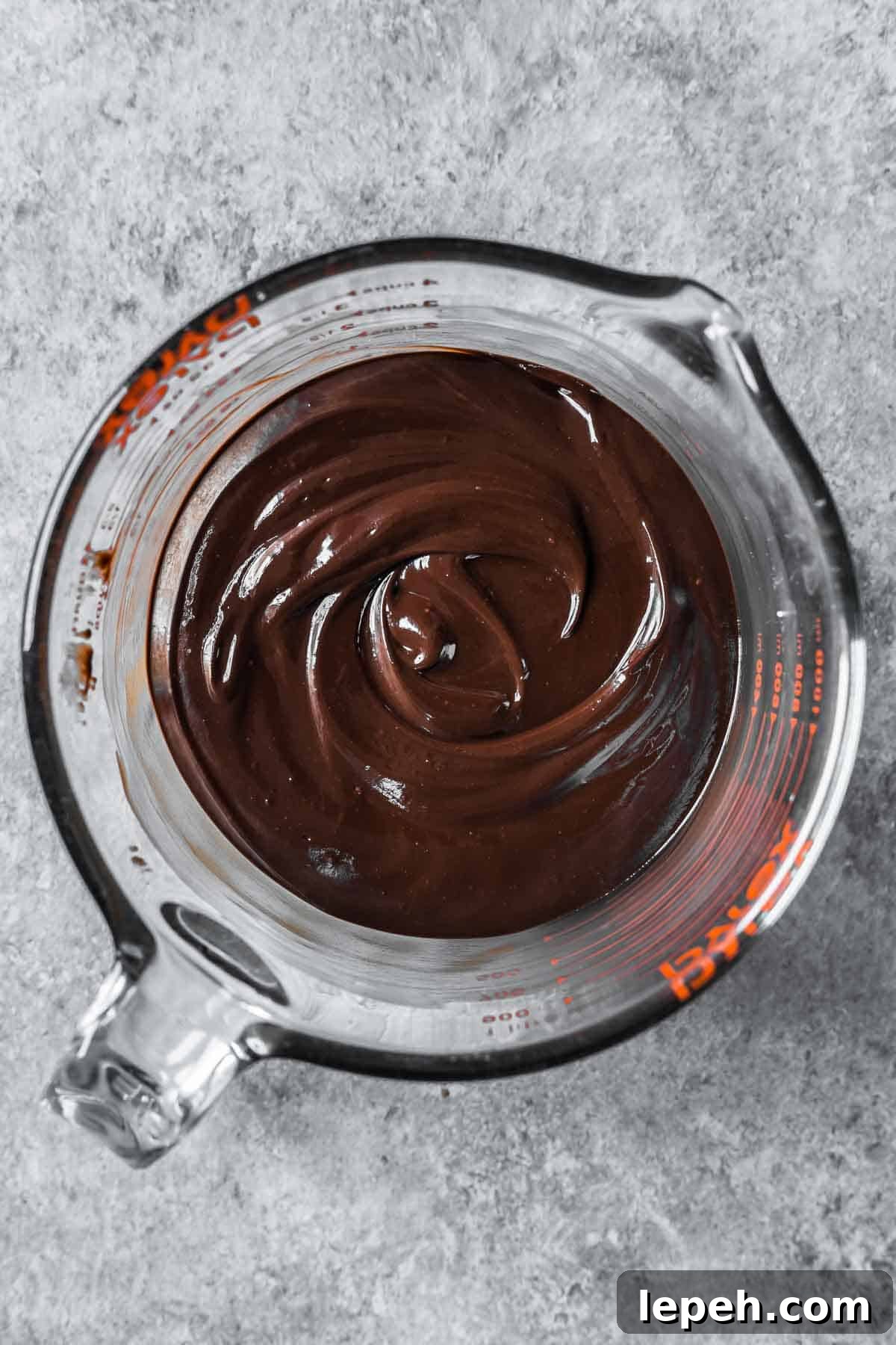 Melted chocolate ganache in a large glass container.