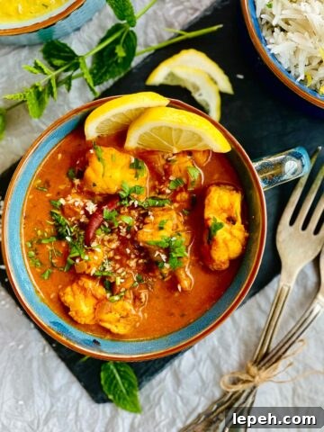 Birdsview Monkfish curry garnished with two slices of fresh lemon and fresh herbs served in a blue soup bowl