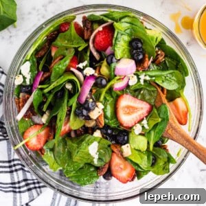 Glass bowl filled with tossed Strawberry Feta Spinach Salad.