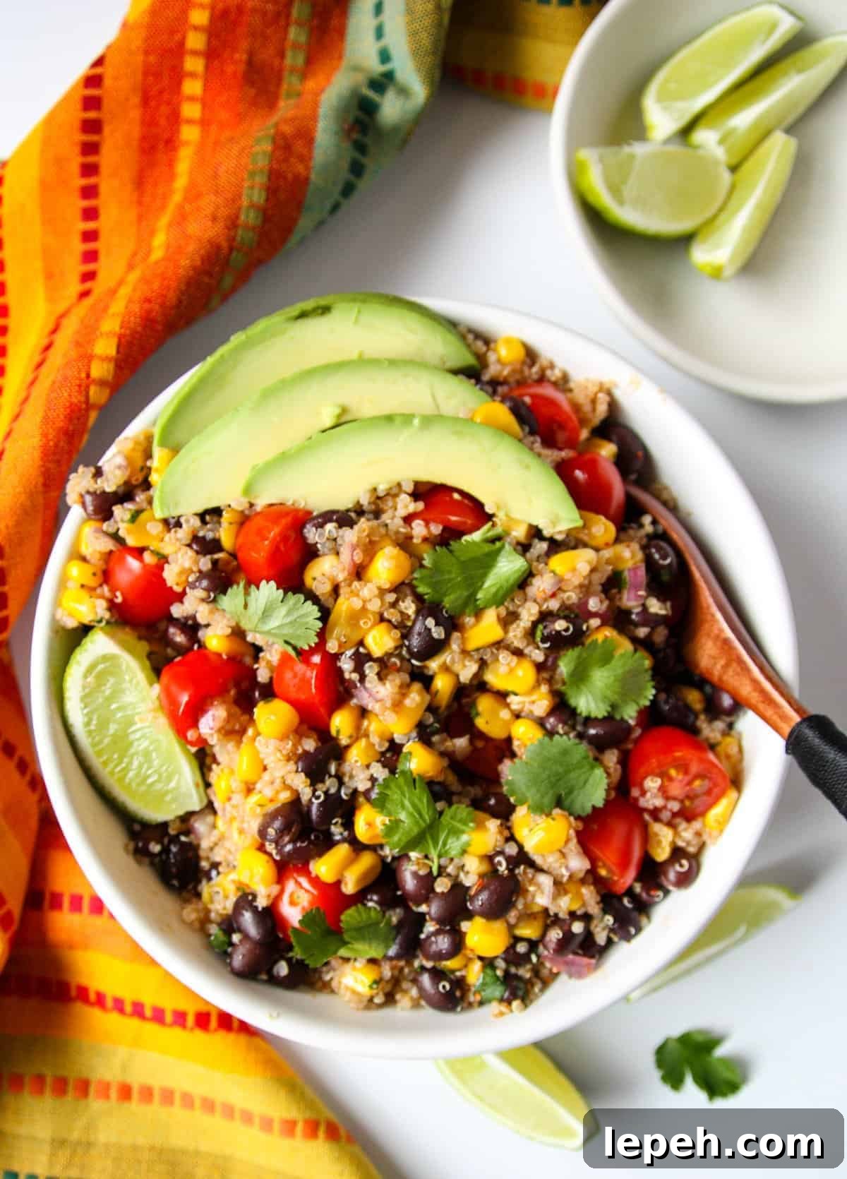 Southwestern quinoa salad in a white bowl topped with avocado slices.
