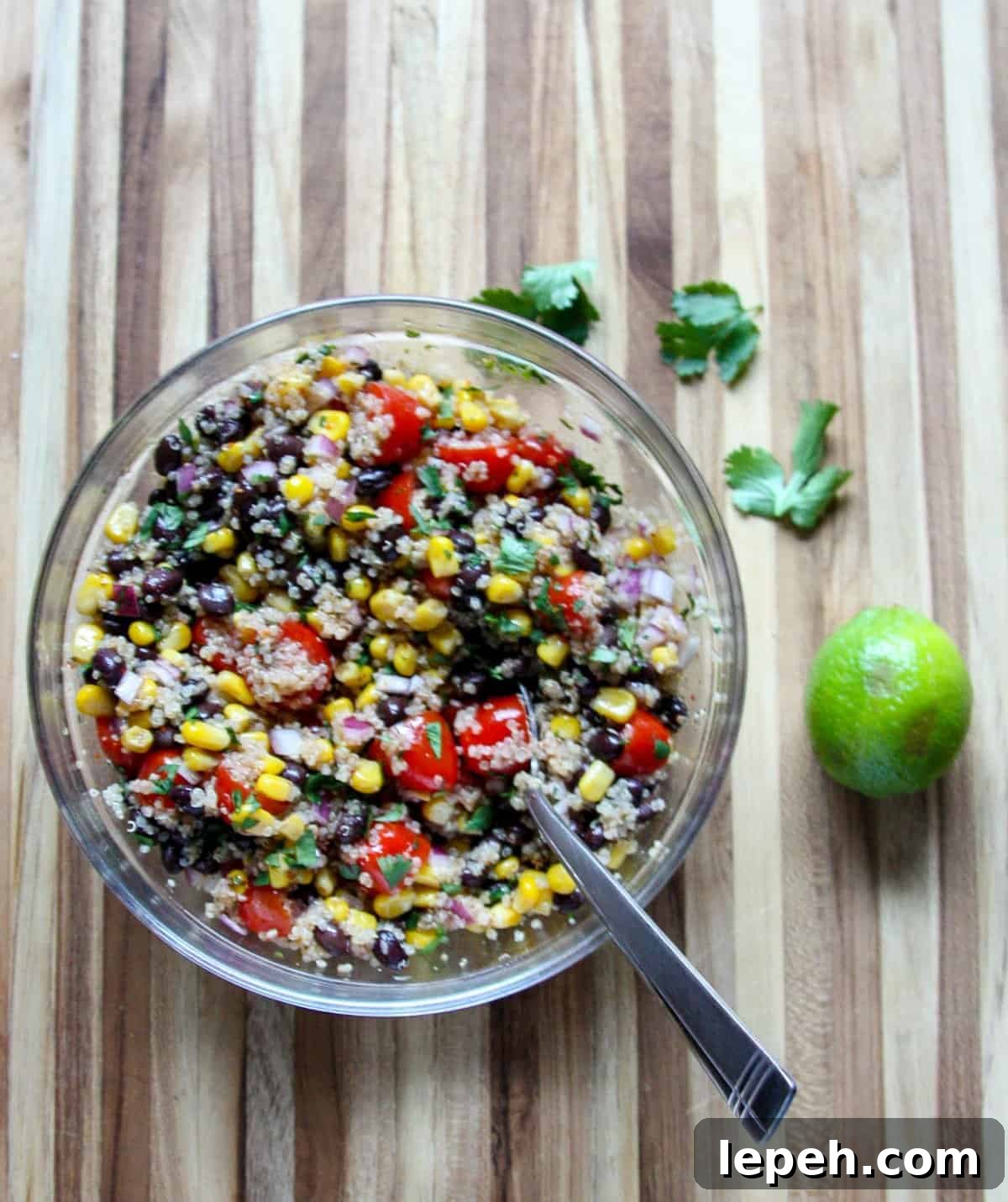 Salad dressing being stirred into salad ingredients in a glass bowl.