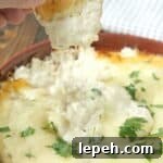 cheesy Chicken Alfredo Dip in baking dish with crostini