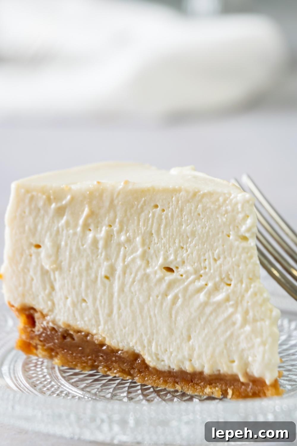 A slice of Philadelphia No Bake Cheesecake on a serving plate. A fork sits next to it.