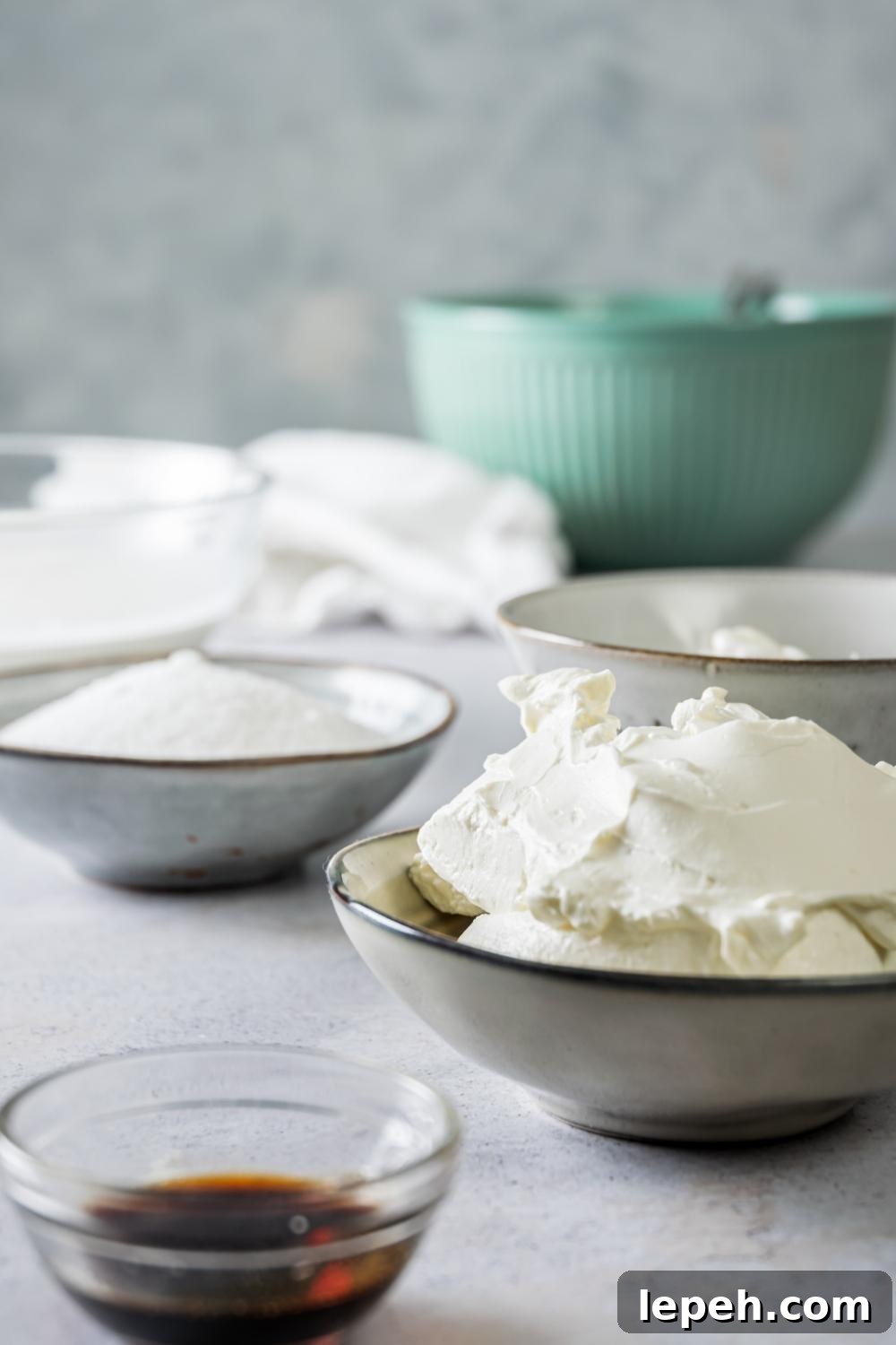 A countertop with multiple bowls containing the ingredients it takes to make Philadelphia No Bake Cheesecake.